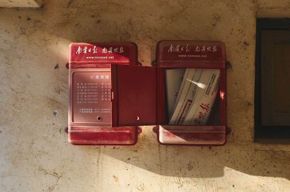 a couple of red mail boxes sitting on top of a wall