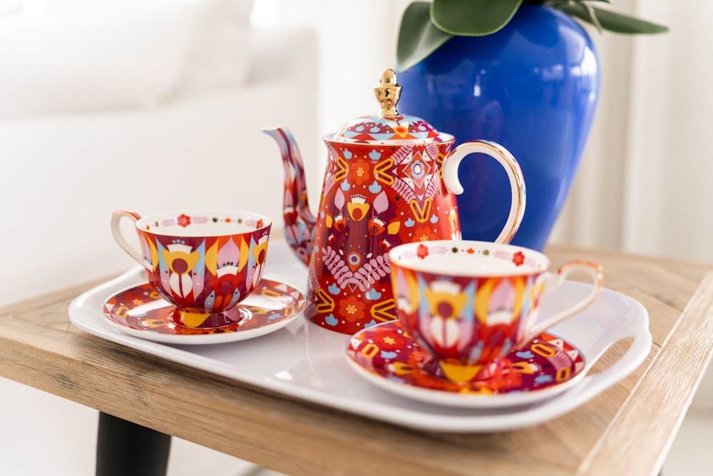 a tea set on a tray with a blue vase in the background