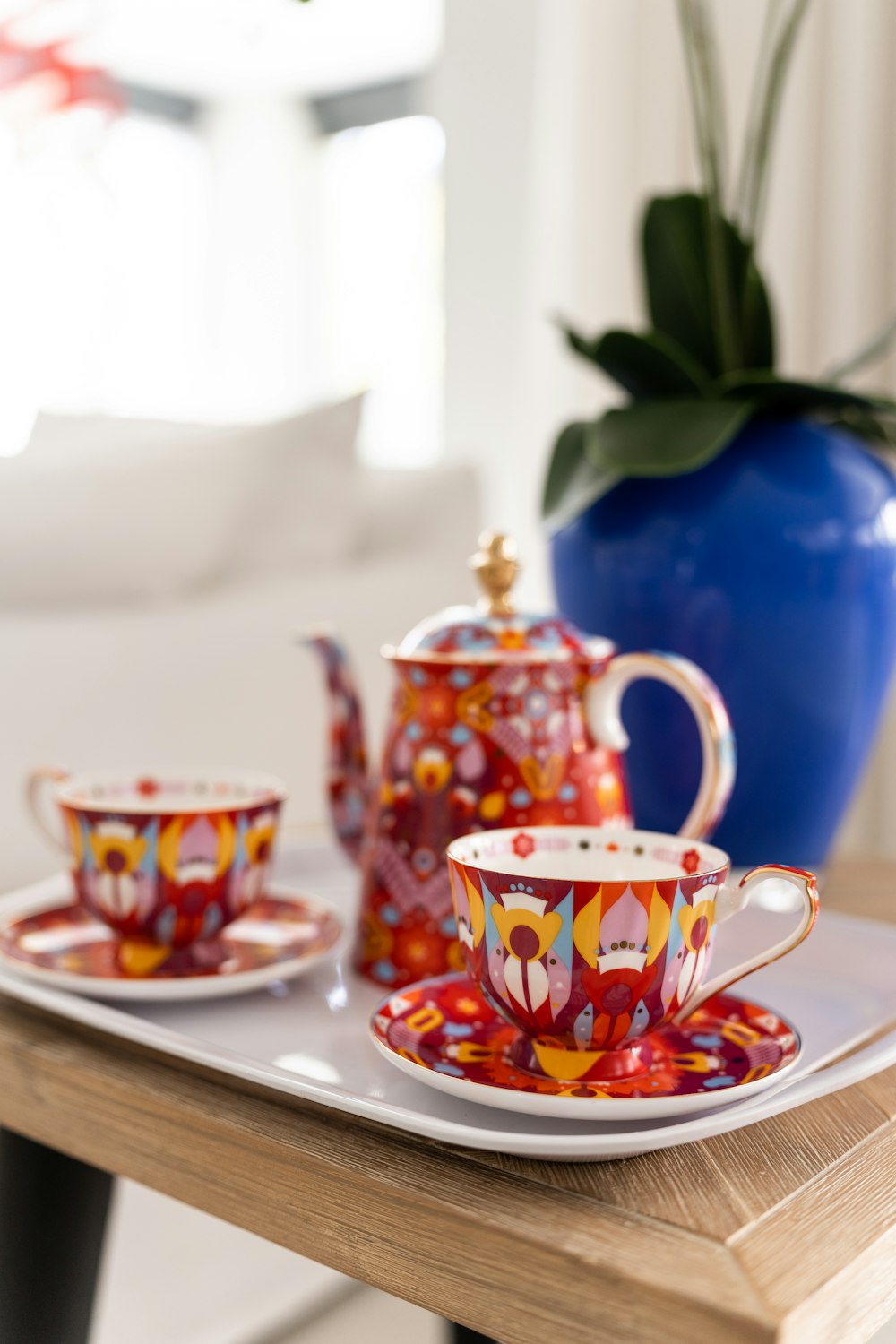 a tea set on a tray with a blue vase in the background