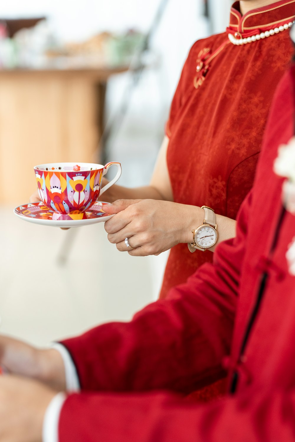 a woman in a red dress holding a cup and saucer