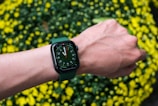 Stylish wrist wearing a smartwatch with a vibrant green digital display.
