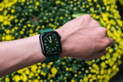 Stylish wrist wearing a smartwatch with a vibrant green digital display.