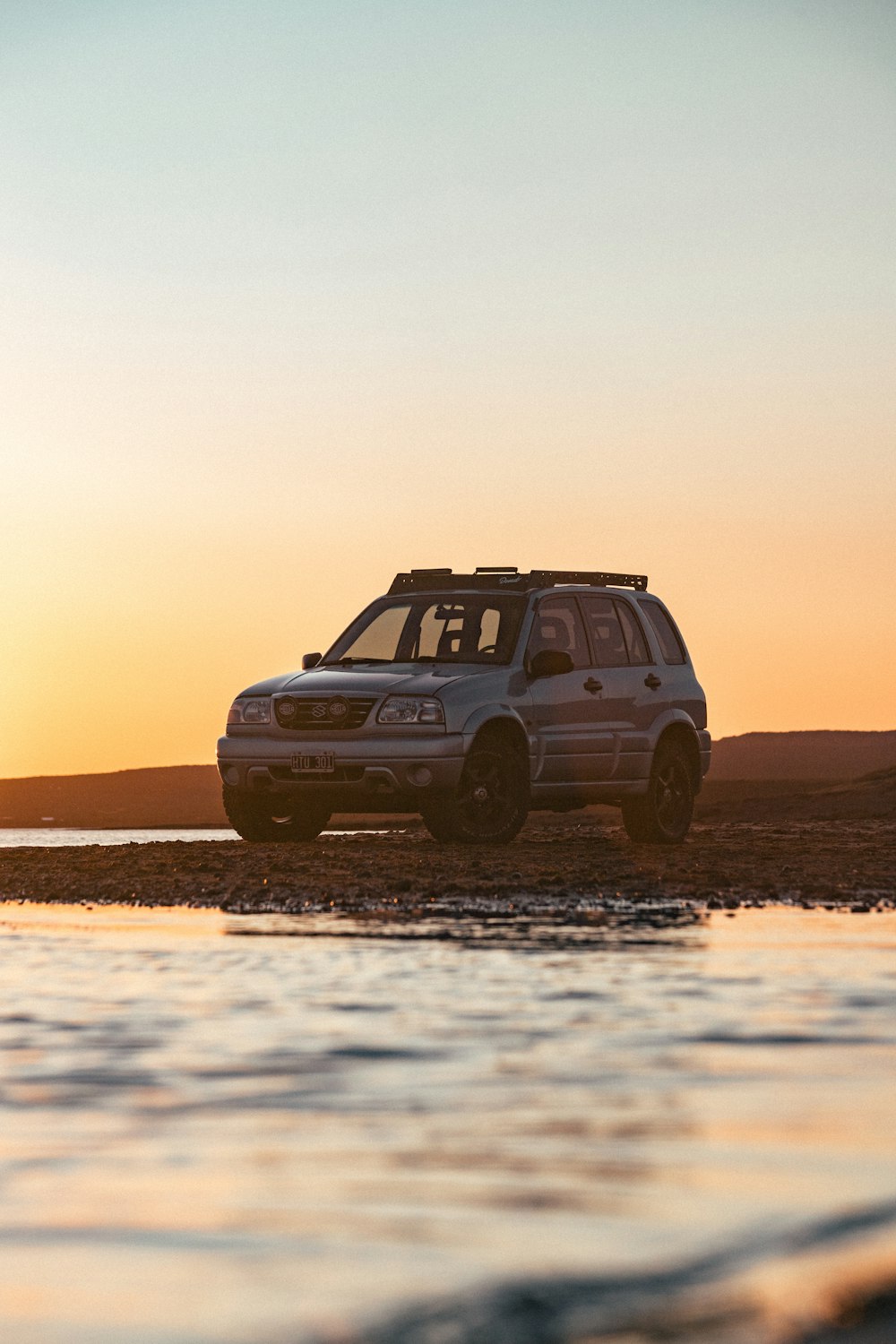 a car is parked on the beach at sunset