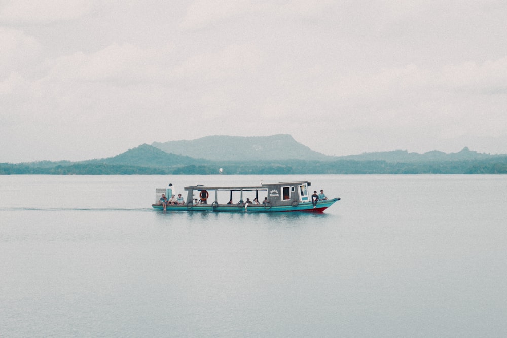 a boat with people on it in the middle of a lake