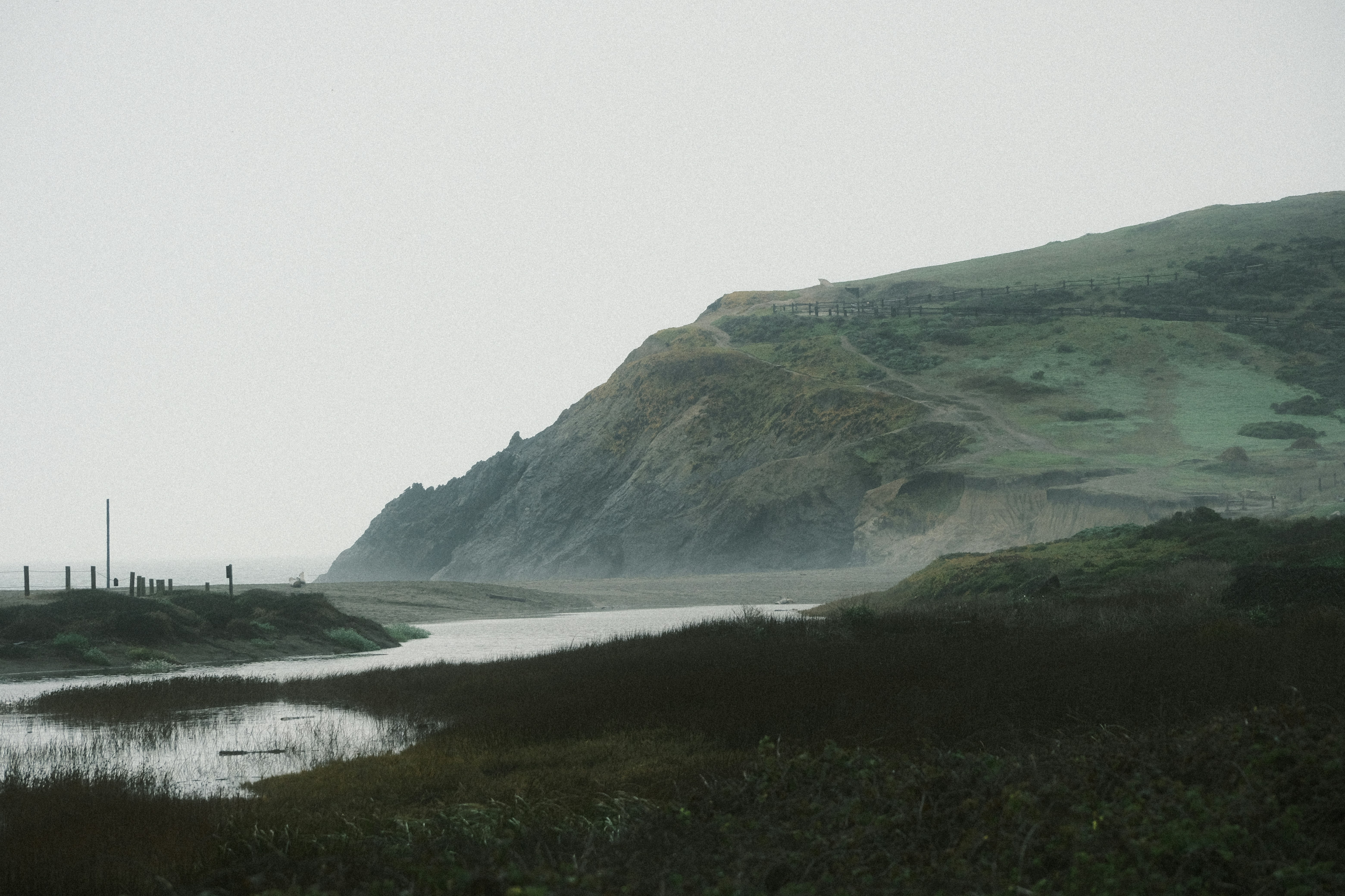a hill with a body of water in the foreground