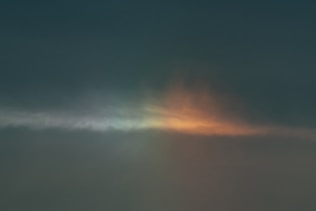 A serene sunrise breaking through dark clouds over a quiet hospital room window.