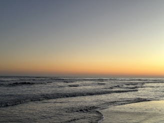 A serene beach scene at dusk with gentle waves.