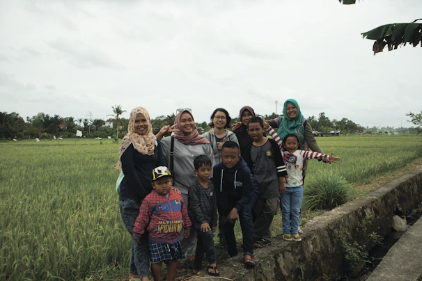 A warm group photo of the žemėsrautas team standing in a lush green field, smiling and holding tablets showing the ez farm app.