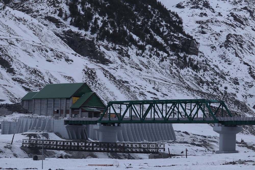 a green bridge over a snow covered mountain