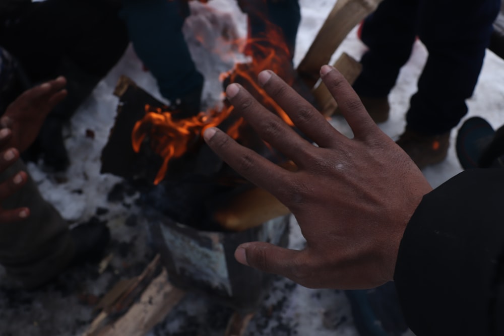 a person holding their hand out in front of a fire