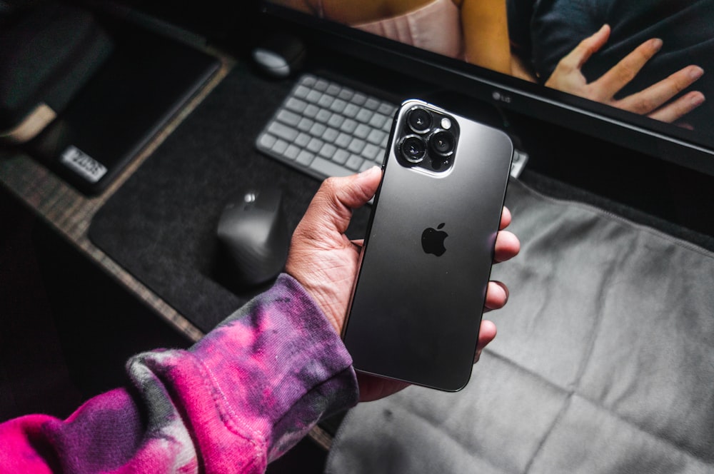 a person holding an iphone in front of a computer