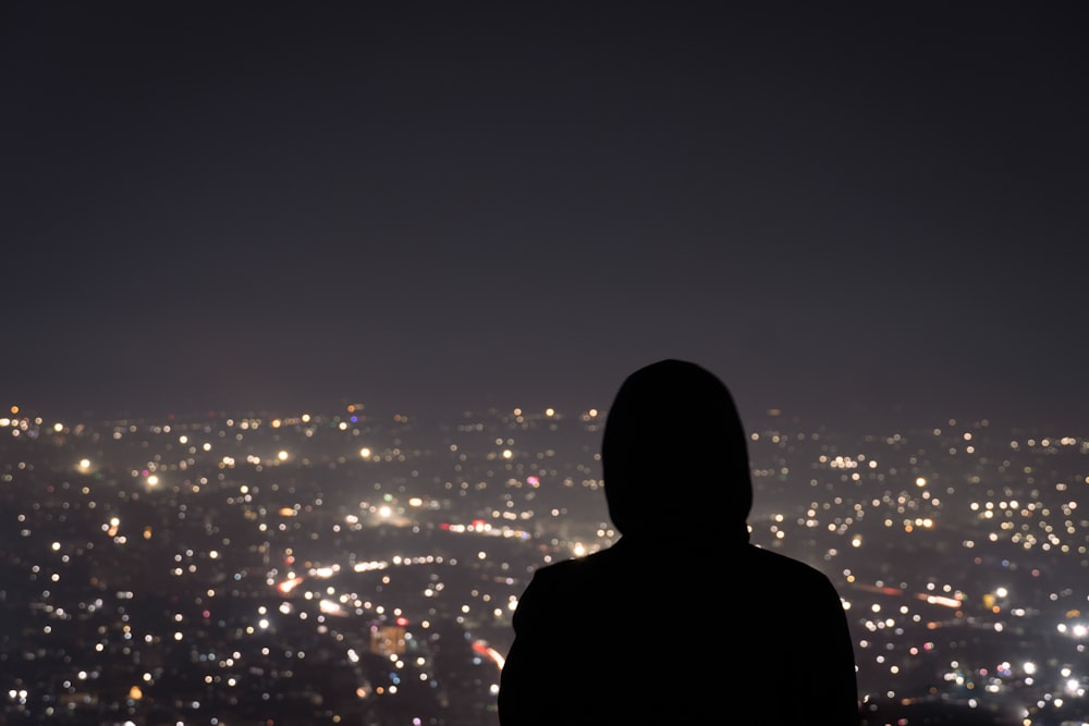uma pessoa em pé na frente de uma cidade à noite