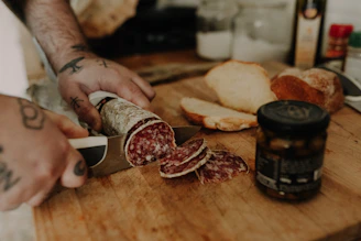 Close-up of a master sausage maker carefully slicing cured saucisson in a rustic kitchen.