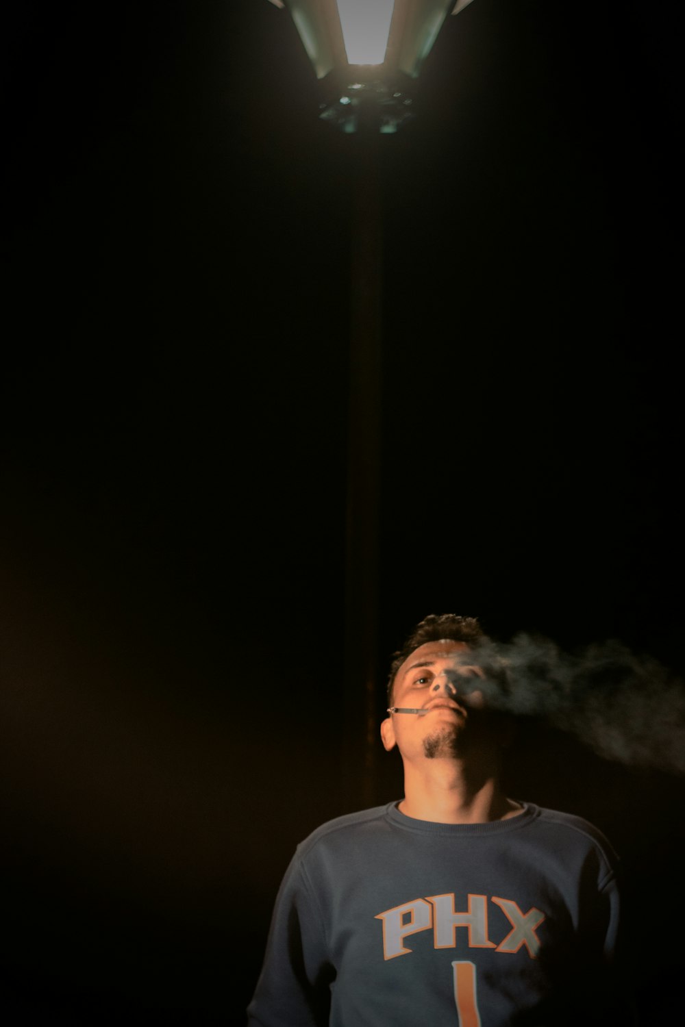 a man standing under a street light with his eyes closed
