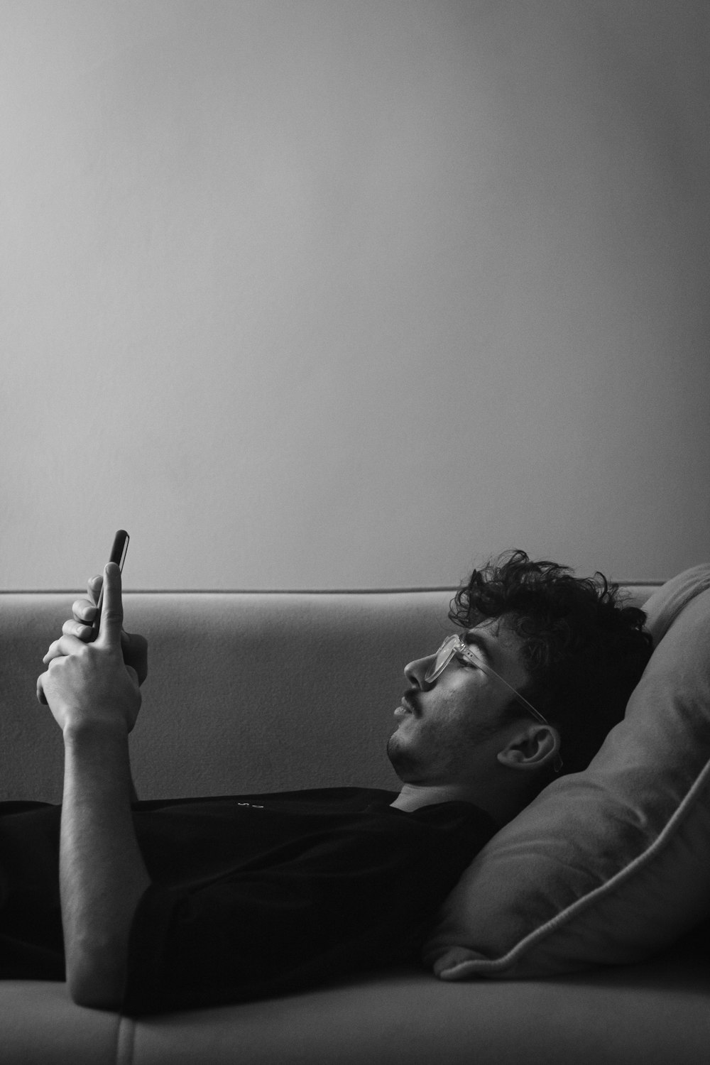 a man laying on a couch holding a cell phone