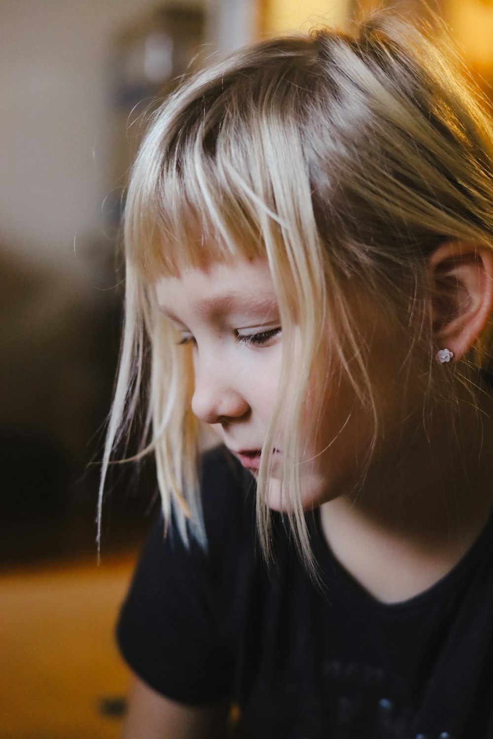 a little girl with blonde hair is looking down