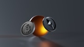 A digital rendering of two metallic coins featuring Bitcoin and Ethereum symbols, set against a sleek, dark background with a glowing orange sphere in the center.