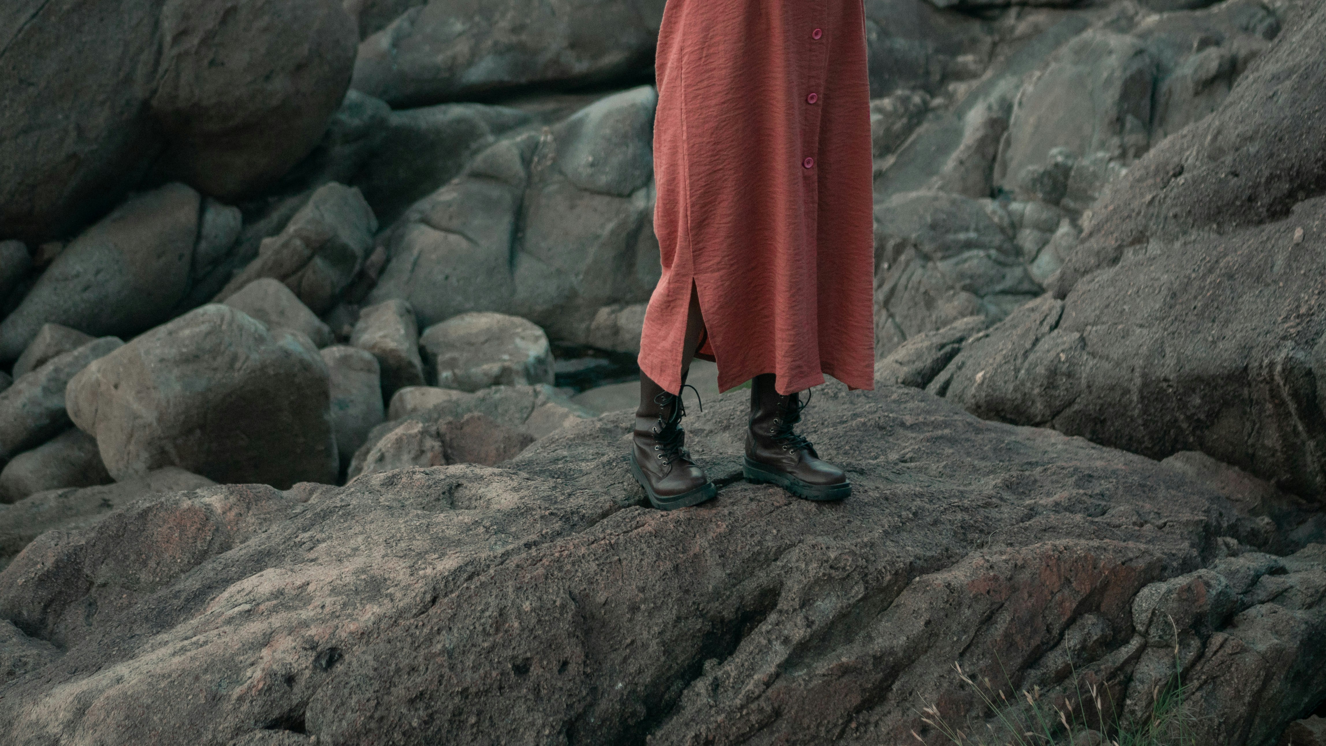 a woman in a red dress standing on a rock