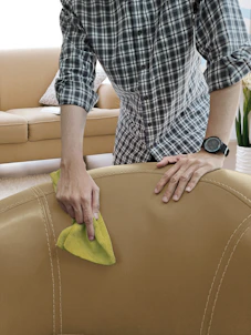 Technician carefully cleaning a modern sofa with professional equipment in a bright living room.