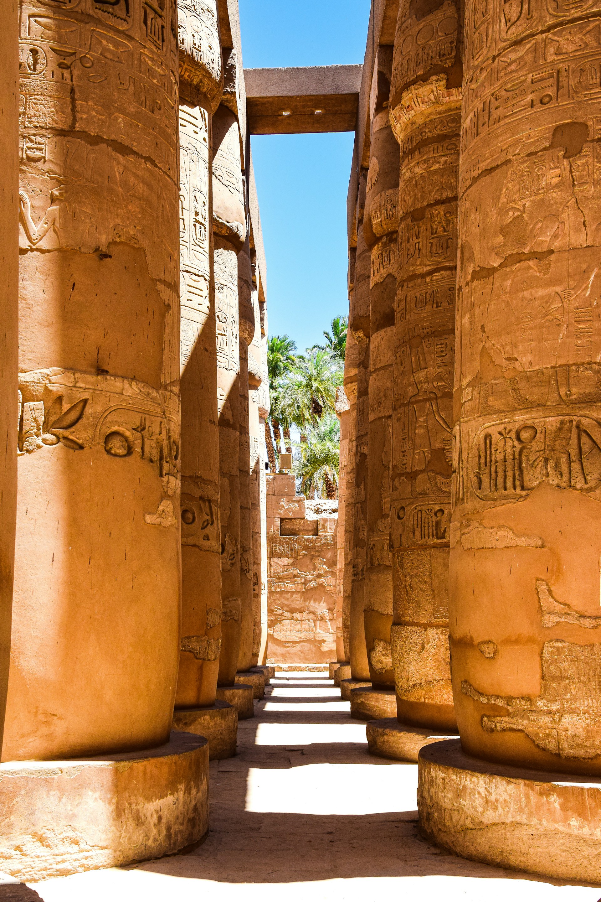 A knowledgeable guide sharing stories with travelers amid the towering columns of Luxor's Karnak Temple under a clear blue sky.