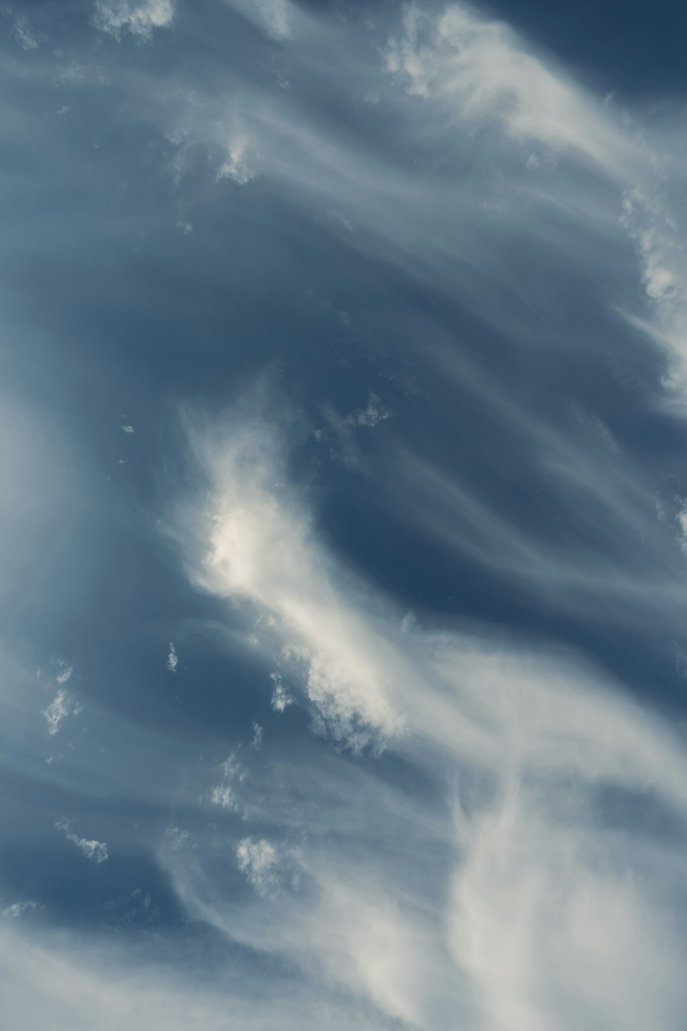 a plane flying through a cloudy blue sky