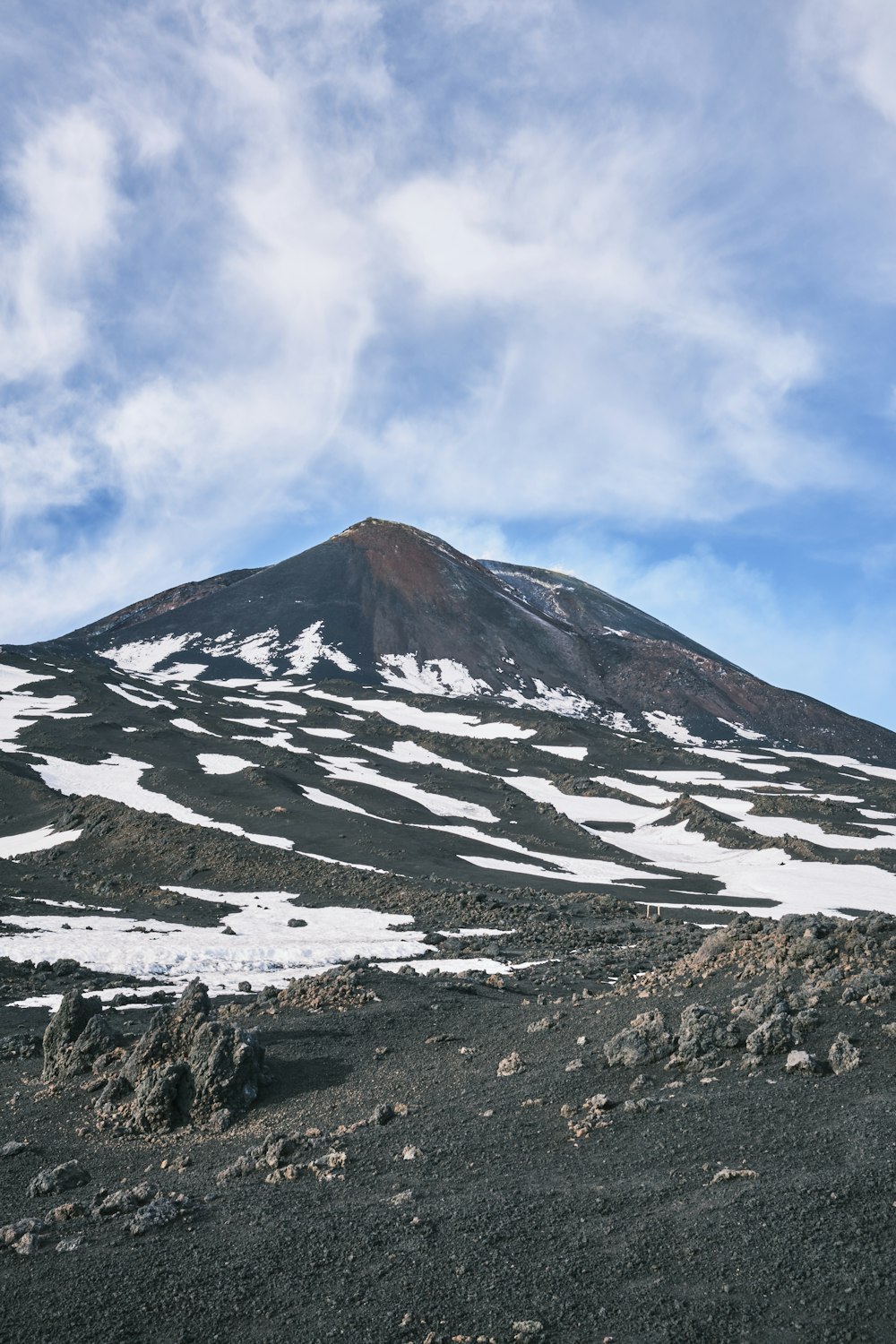 a mountain covered in snow under a cloudy blue sky