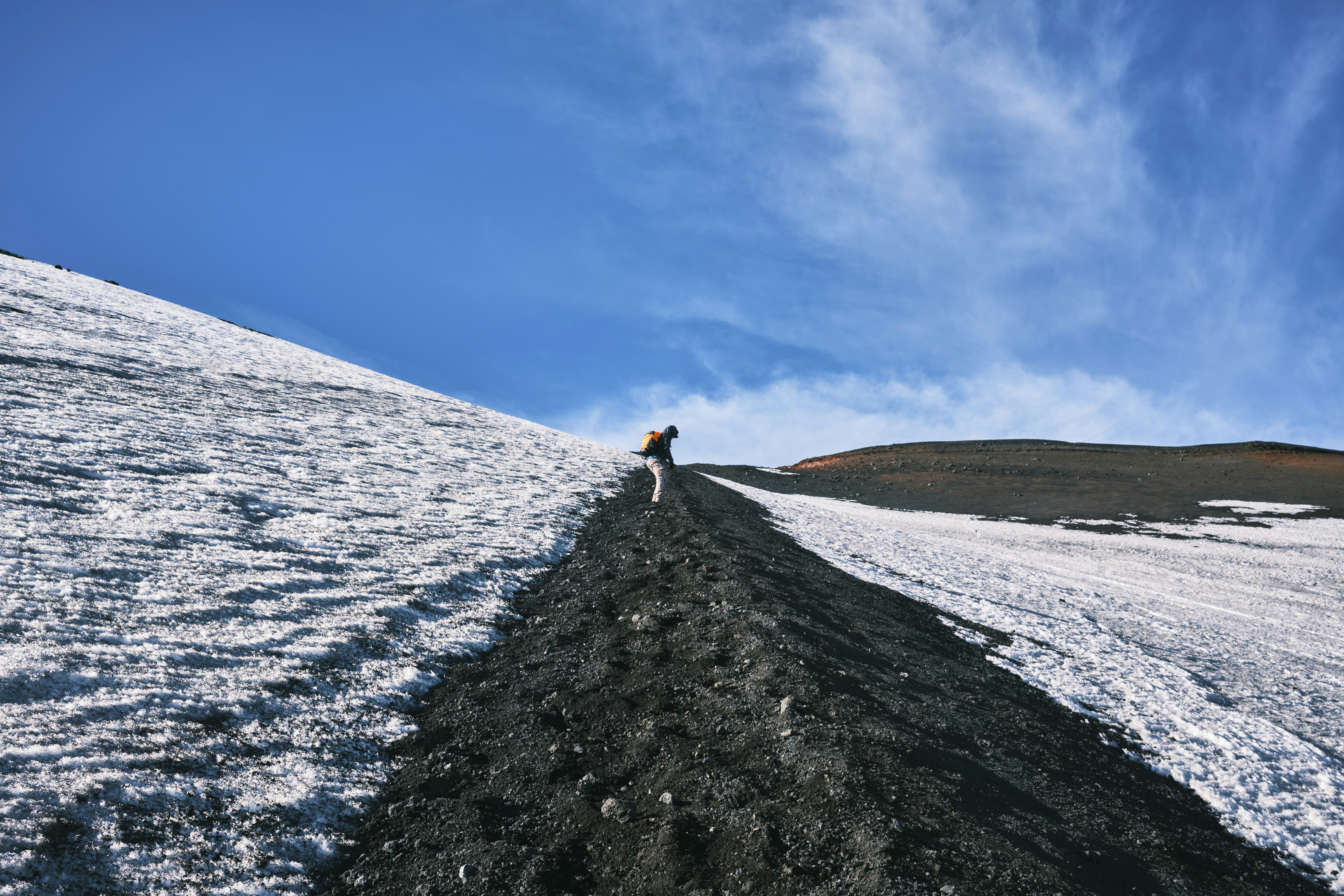 una persona in piedi sulla cima di una collina coperta di neve