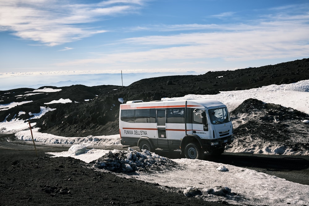 a white bus driving down a snow covered road