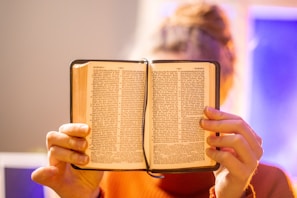 Close-up of hands holding an open Bible with soft natural light.
