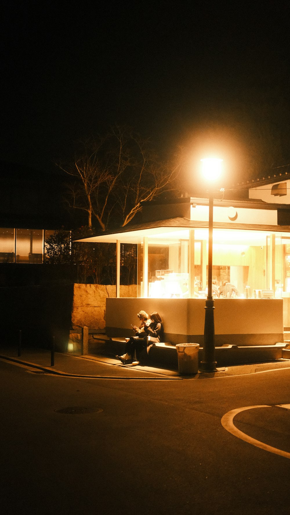 a person sitting on a bench in front of a building at night