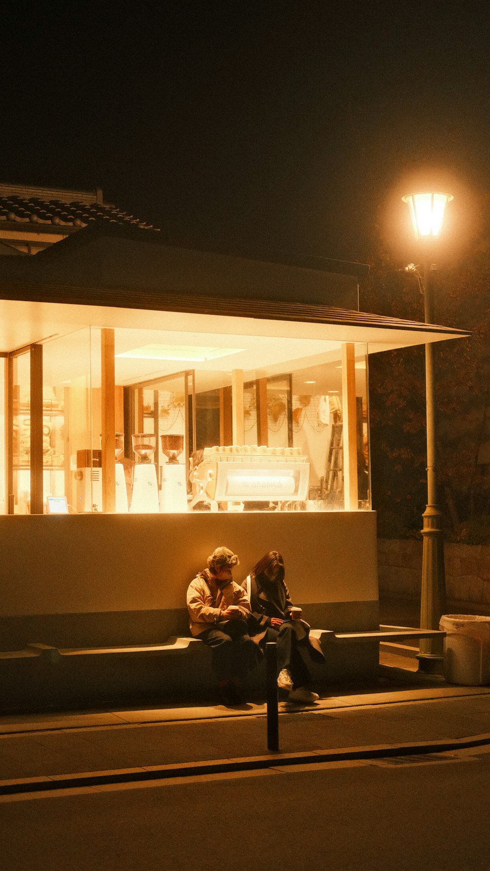 two people sitting on a bench in front of a building