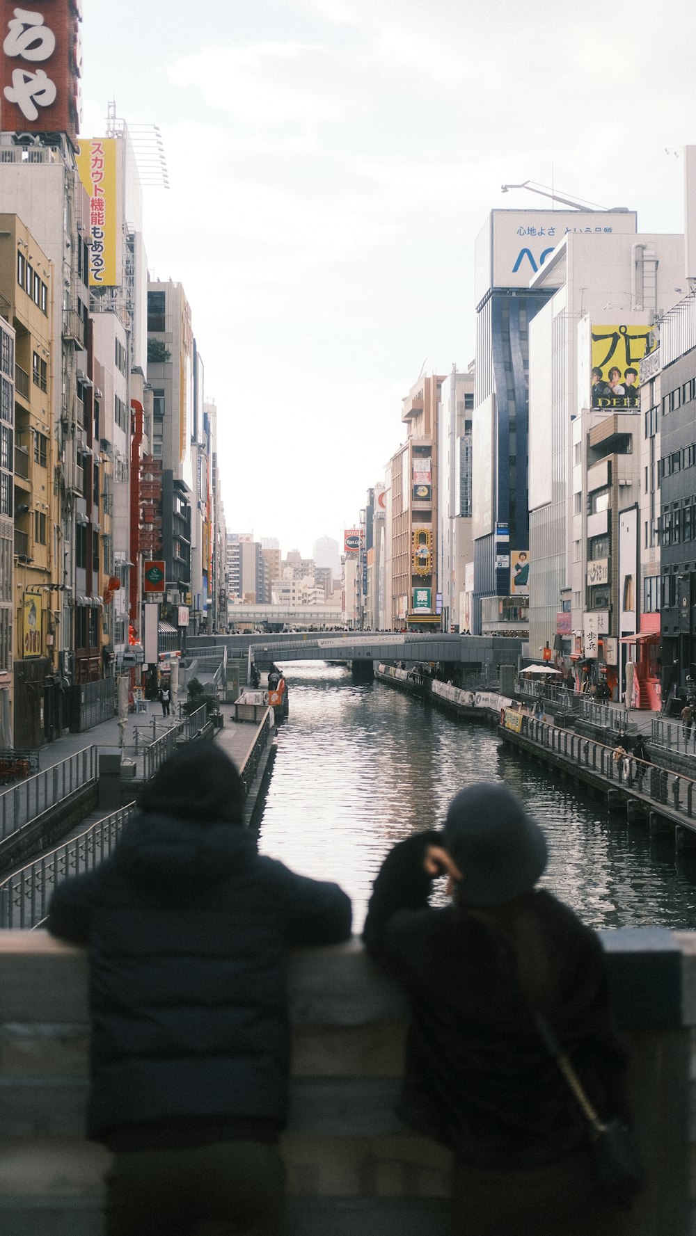 two people sitting on a bench looking at the water