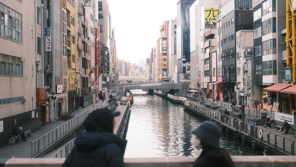 a couple of people standing on a bridge over a river