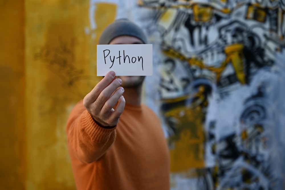 a man holding up a sign with the word python written on it