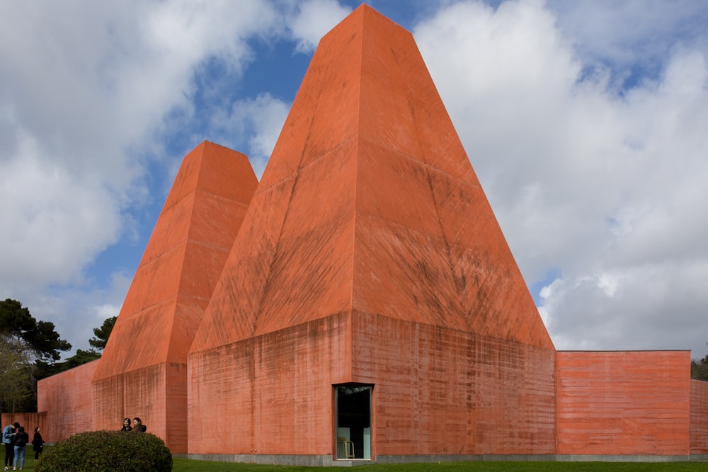 a large pyramid shaped building sitting on top of a lush green field