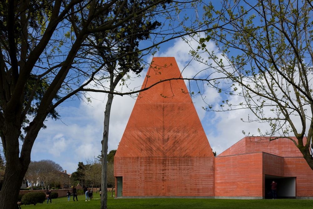 a red building with a triangular roof and a tree in front of it