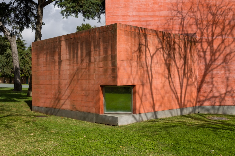 a red building with a green door in the grass