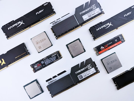 Various computer components including RAM sticks, processors, and SSDs are arranged against a white background. Brands such as HyperX, G.Skill, AMD Ryzen, Seagate FireCuda, and Samsung are visible.