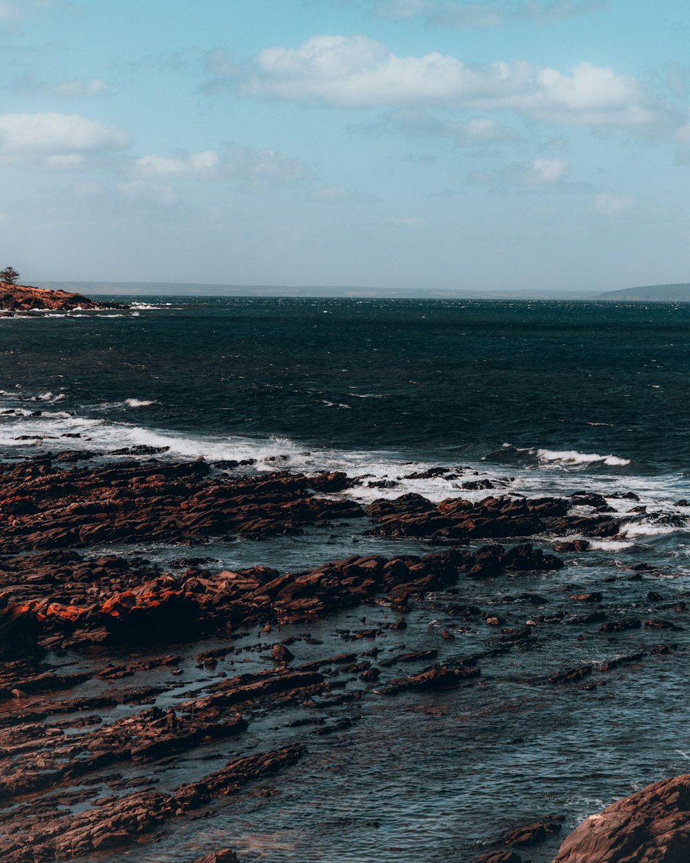 a person walking along a rocky beach near the ocean