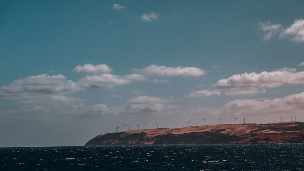 a large body of water with wind mills in the background