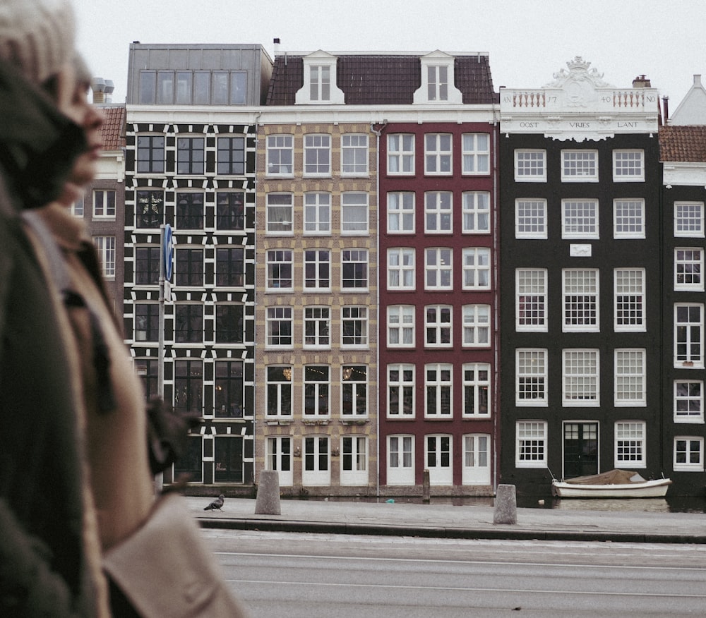 a woman walking down a street next to tall buildings