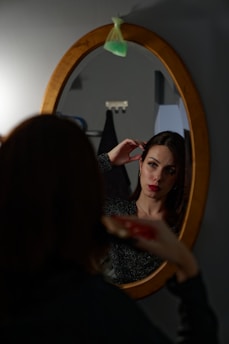 a woman standing in front of a mirror brushing her hair