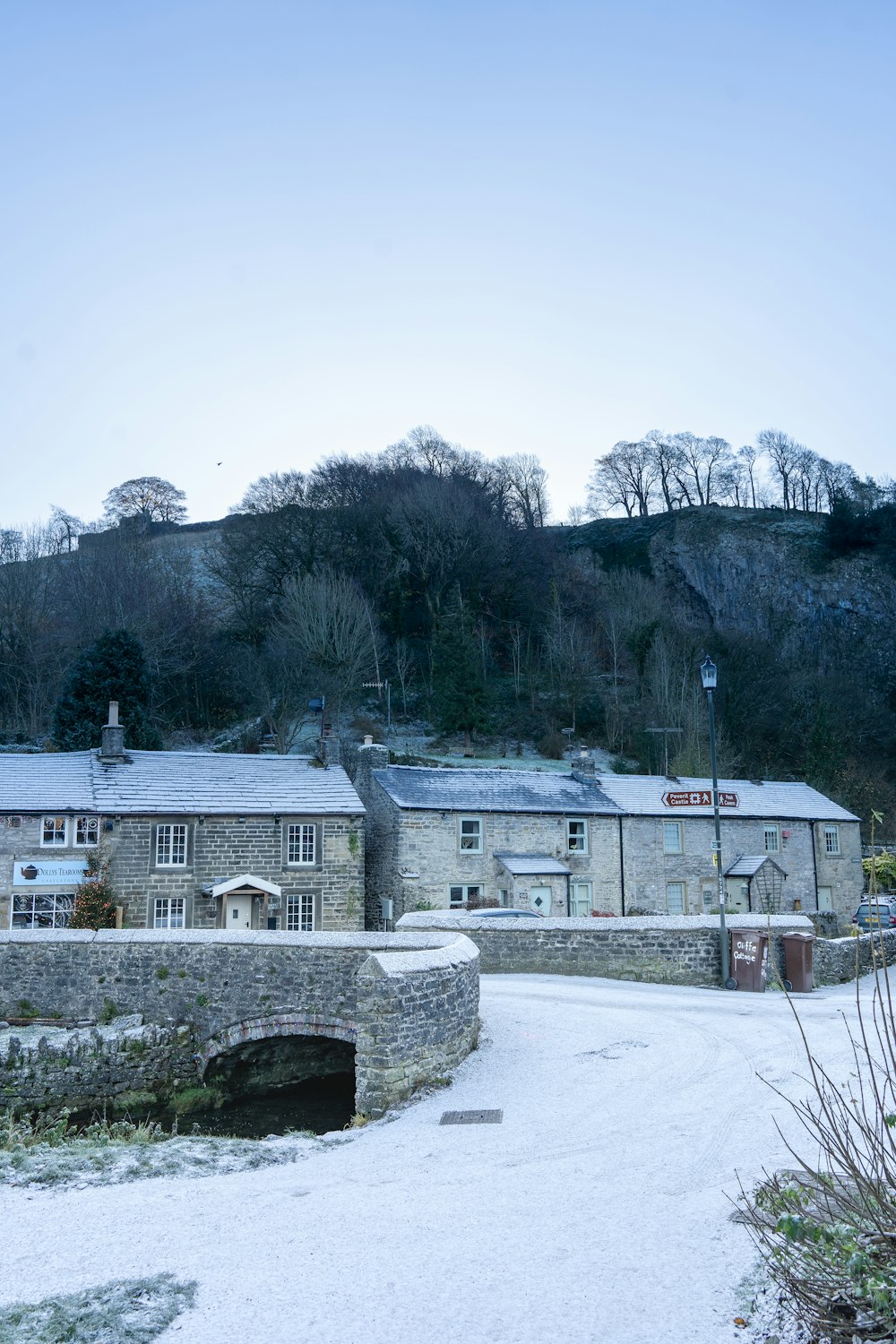 a snow covered road next to a stone building