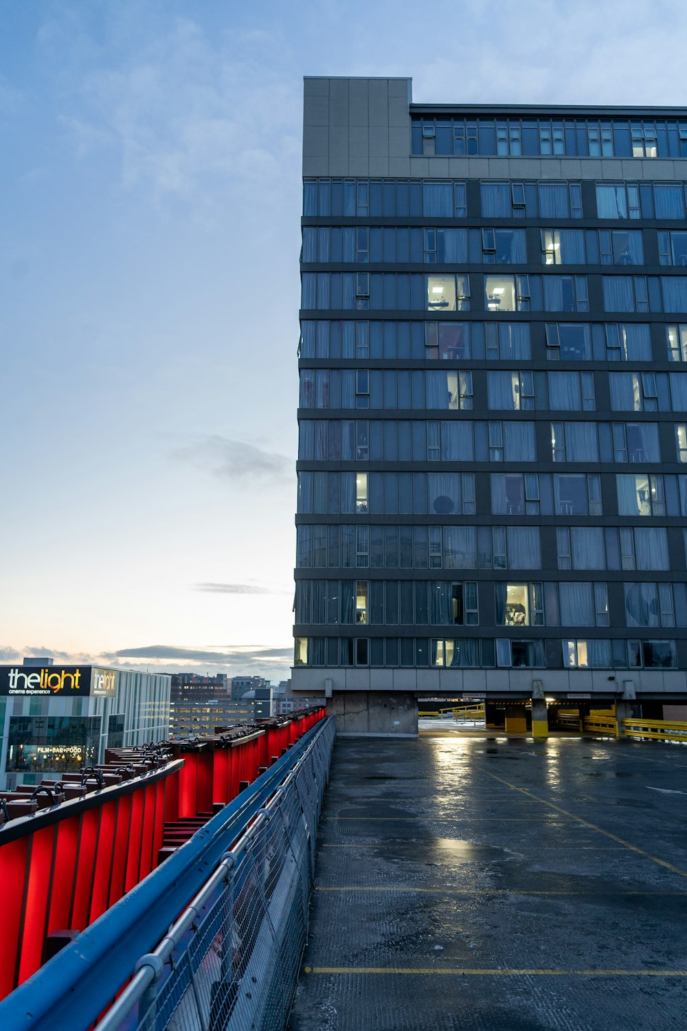 a tall building with lots of windows next to a parking lot