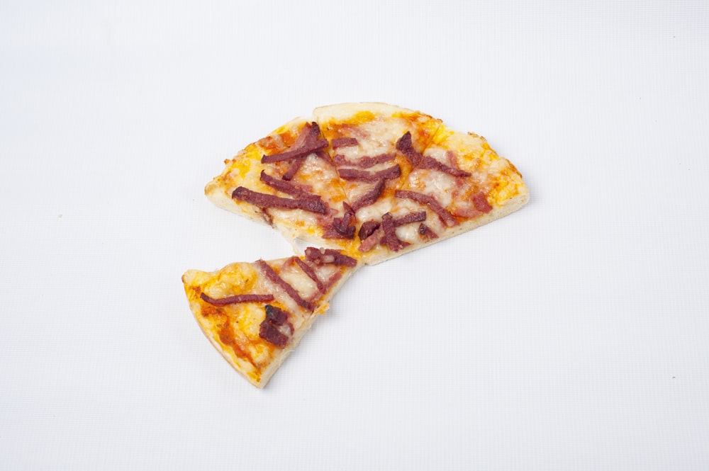 zwei Scheiben Pizza mit Speck drauf
