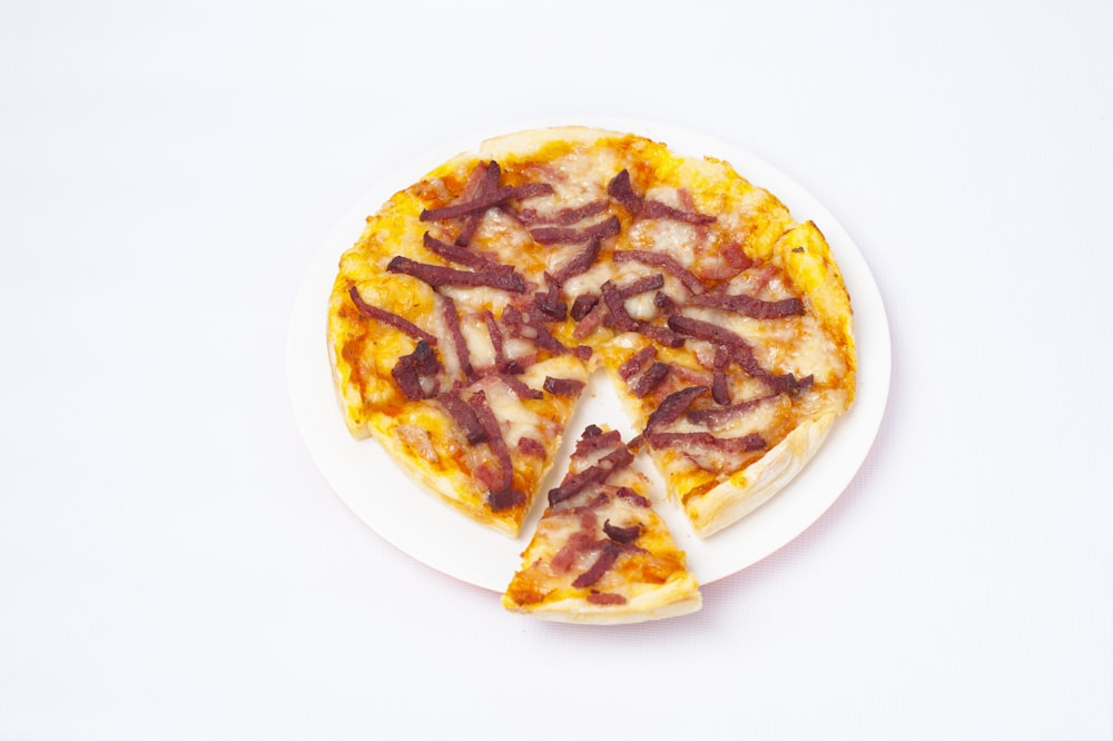 a pizza with bacon on a white plate