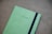 a green notebook with a black stripe on the cover