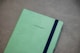 a green notebook with a black stripe on the cover