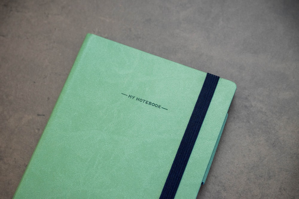 ein grünes Notizbuch mit einem schwarzen Streifen auf dem Cover