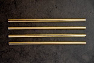 a group of four gold colored straws sitting on top of a table